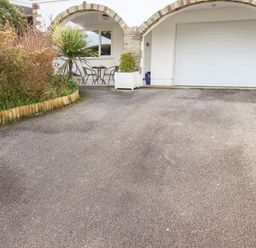 A driveway with a garage door and outdoor seating area under arches at EdyVean in Portmellon near Mevagissey
