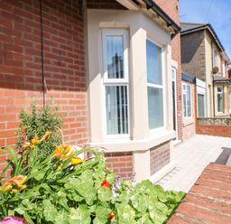 A front porch with tiled floor and a flower bed outside a brick house at Lobster Pot Retreat in Newbiggin-By-The-Sea