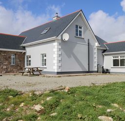 A house with a satellite dish and gravel area at Tí Tom Nárta in Trabane near Lettermore, County Galway