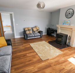 A living room with a sofa and an armchair at Tí Tom Nárta Trabane near Lettermore, County Galway