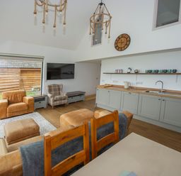 A living room and kitchen area with chairs a sofa and wooden cabinets at Owl Lodge in Wedmore