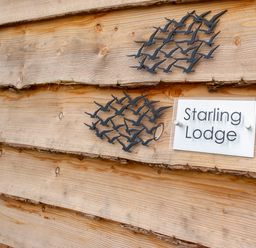 A wooden wall with two black bird decorations and a sign that says Starling Lodge at Starling Lodge in Wedmore