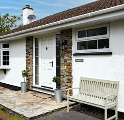 The entrance of a white house with a bench and two potted plants near the door at Samphire Rock