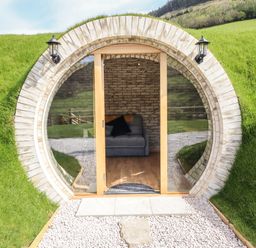 A round entrance with glass doors showing a sofa inside built into a grassy hillside at Nant y Garnedd Mallwyd near Dinas Mawddwy