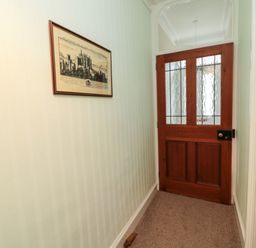 A hallway with a framed picture on the wall and a wooden door with glass panels at 19 Duke Street in Alnwick
