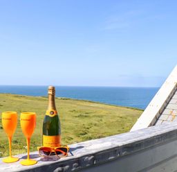 A champagne bottle and glasses on a balcony with a sea view at Penthouse 23 in Newquay