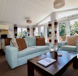 A living room with light blue sofas a wooden coffee table and large windows at 23 Bossiney Bay in Tintagel