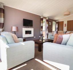 A living room with sofas a coffee table wall mounted tv and electric fireplace at 23 Bossiney Bay in Tintagel
