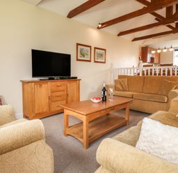 A living room with sofas a wooden coffee table and a TV cabinet at Tilly Mint Cottage Nr Ullswater