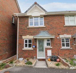 A brick two storey house with a white front door and small garden beds at Chesil Retreat in Weymouth