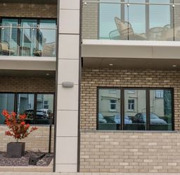 The exterior of a modern building with balconies and glass railings and red-leaved plant at 30 Cliff Edge in Newquay