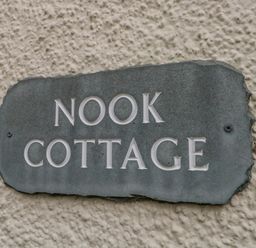 A stone sign with the text Nook Cottage on a textured wall at Nook Cottage in Rosthwaite near Keswick
