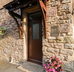 An entrance with a wooden door and stone wall at Summerseat in Kirkby Stephen