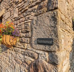 A flower basket and nameplate on a stone wall at Summerseat in Kirkby Stephen