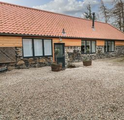 A single story building with a tiled roof stone and wood walls and gravel in front at The Bakery in Middleton near Belford