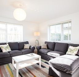 A living room with two dark sofas a white coffee table a floor lamp and striped rug at Obos Retreat in St Minver near Rock
