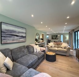 A living room with grey sofas wooden floor and painting on the wall at Primrose in Hellandbridge near Bodmin