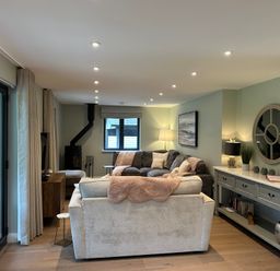 A living room with two sofas a wood burning stove and a console table with lamps and a mirror at Primrose Hellandbridge near Bodmin