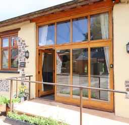 Exterior view of a barn with large wooden framed glass doors and windows at Quoit X Barn in Stoodleigh near Bampton