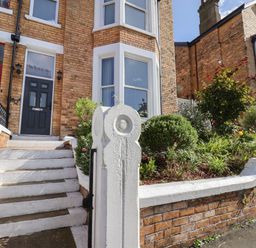 A front entrance with white steps black handrail and greenery next to a brick house at Spinnaker House Scarborough