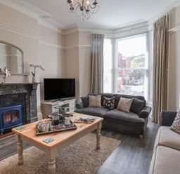 A living room with two sofas a wooden coffee table a TV and a fireplace at Spinnaker House in Scarborough