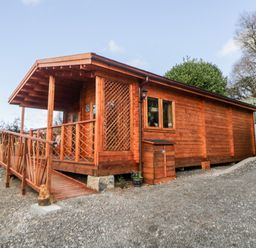 A wooden cabin with a ramp and porch in an outdoor setting at Bearscombe View in Modbury