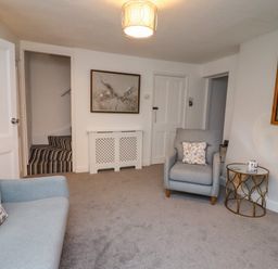 A living room with gray sofas and armchairs a glass side table and a wall clock at Monteva Whitby