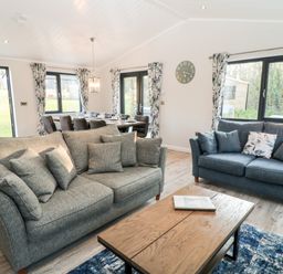 A living room with two sofas a wooden coffee table a dining table with chairs and large windows at Mayflower Broadwoodwidger near Ashwater