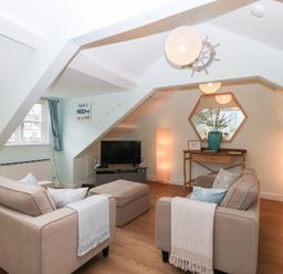 A living room with sofa and television at Smugglers Loft in Looe