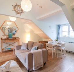 A living room with a sofa and dining table at Smugglers Loft in Looe