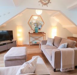 A living room with a television and a sofa at Smugglers Loft in Looe