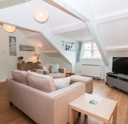 A living room with sofa and TV at Smugglers Loft in Looe