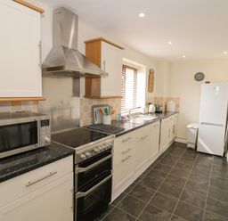 A kitchen with appliances including microwave stove refrigerator and stools at The Wheat House in Welford-On-Avon