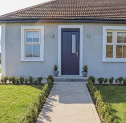 A front view of a house with a blue door two windows and a garden path at An Teachain in Adamstown County Wexford