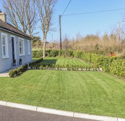 A front yard with trimmed grass and small hedges next to a house at An Teachain in Adamstown County Wexford