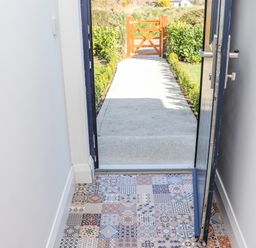 A view of an open door with patterned tiles inside and a pathway leading to a wooden gate outside at An Teachain in Adamstown County Wexford