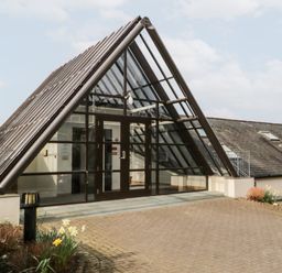 An entrance with glass double doors and a triangular glass roof over the doorway at Rothay in Ambleside