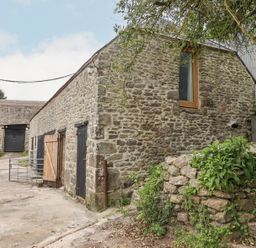 A stone barn with wooden doors and a window surrounded by stone steps and greenery at The Coach House at Thorn Farm Bridford near Moretonhampstead