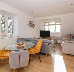A living room with sofas a glass dining table with chairs and a television at Seaspray Stoke Fleming Near Dartmouth