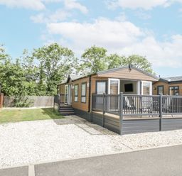 A mobile home with a porch and decking in a gravel area at Serendipity