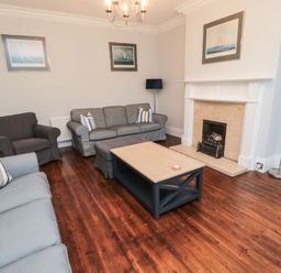 A living room with sofas a coffee table a fireplace and framed pictures on the wall at Glenander in Bamburgh