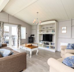 A living room with sofas a coffee table a television and a wood stove at Skylarks in Fornham St Genevieve near Bury St Edmunds
