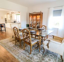 A dining room with a glass table and wooden chairs next to a decorated cabinet at Wisteria Cottage in Annagry County Donegal