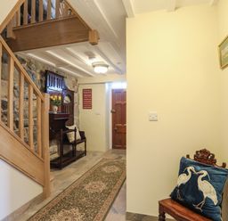 A hallway with wooden staircase a long patterned rug and a wooden bench with a cushion at Bryn Moelyn Cottage in Yr Efail near Morfa Nefyn
