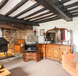 A living room with a wood burning stove and wooden furniture at Gilfachwydd in Islawrdref near Dolgellau