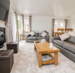 A living room with two leather sofas a wooden coffee table and a wall-mounted television at Ridge's Retreat No 7 Kigbeare Lodges Ashbury Resort near Fowley Cross Sourton Down and Okehampton