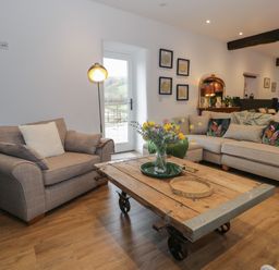 A living room with two sofas a wooden coffee table with flowers on it and wall art at Plas Glan Yr Afon in Llangernyw