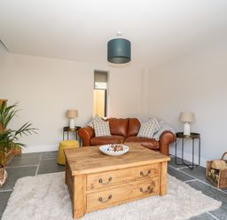 A living room with a brown leather sofa two side tables with lamps a wooden coffee table and a plant at Little Lugg in Cross Keys near Hereford