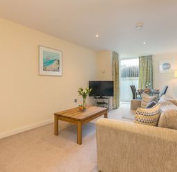 A living room with a sofa coffee table television and dining table at Golden Sands in Carbis Bay