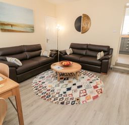 A living room with two brown sofas and a round patterned rug at Stone's Throw in Amble